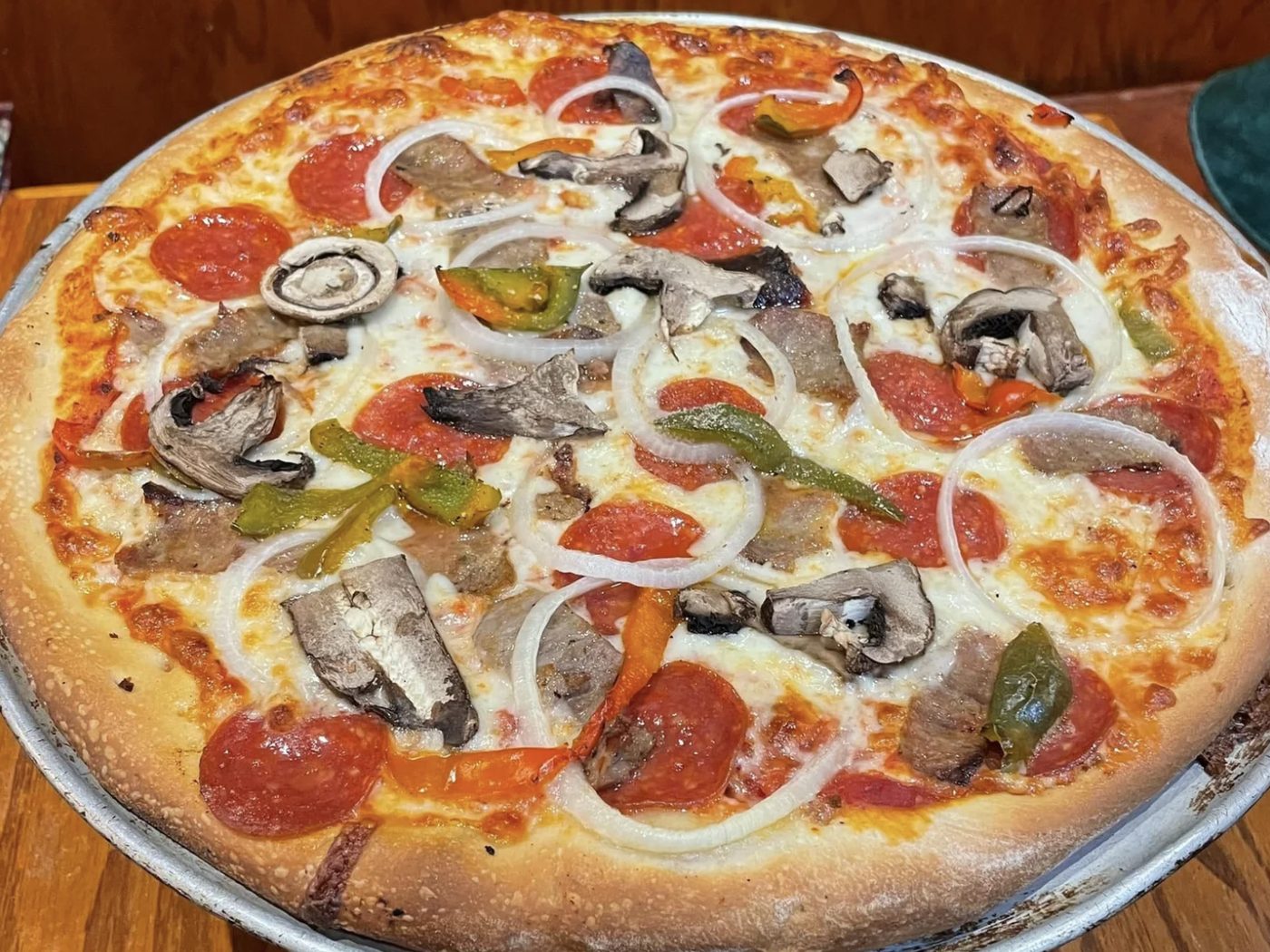 A Luigi's pizza with pepperoni, mushrooms, peppers and onion, fresh from the oven